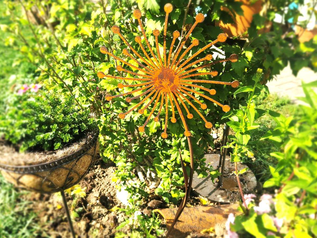Metallstecker Blume Rost im bepflanzten Gartenbeet